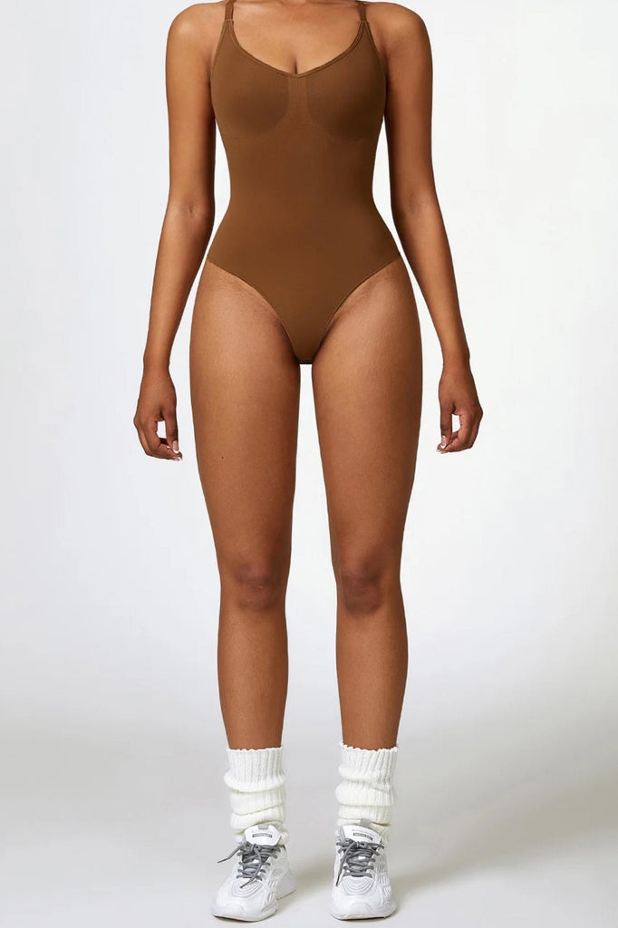 Kvinde iført brun bodysuit med tynde stropper og høj benskæring. Sporty og feminin pasform – ideel til både træning og hverdagsbrug.