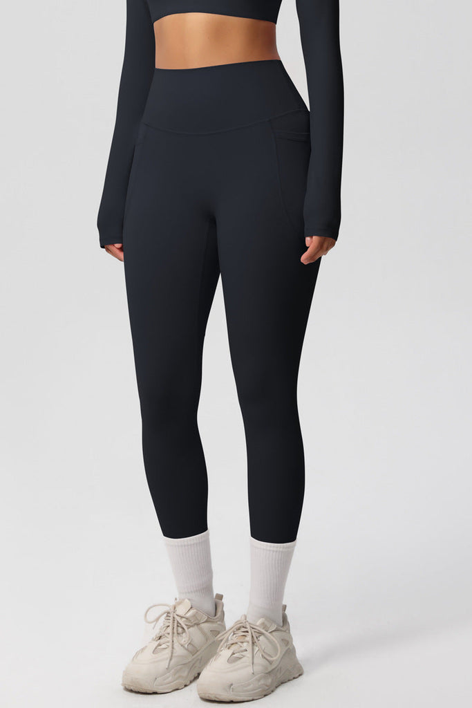 Model iført sorte leggings – set forfra, stående i sneakers og hvide strømper.

