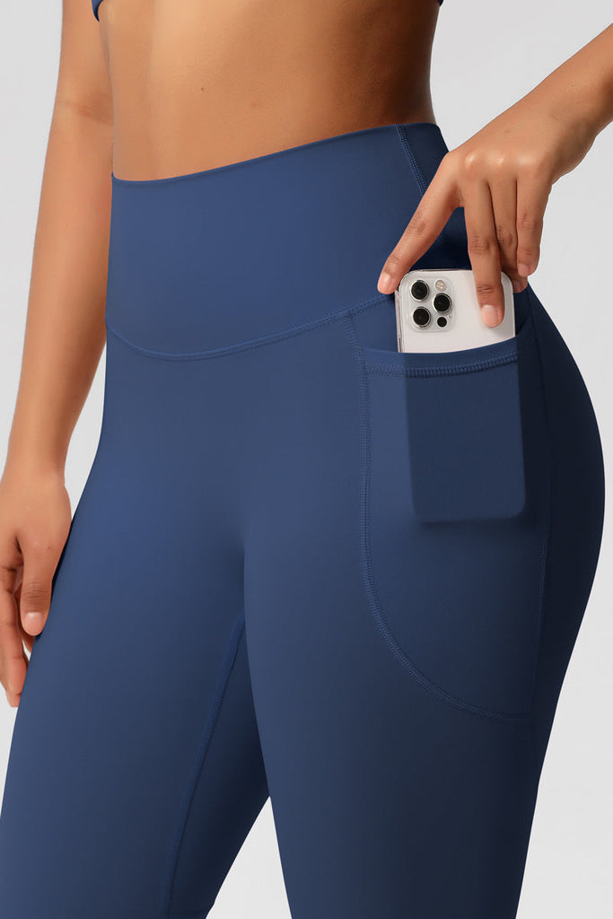 Nærbillede af sidelomme på blå leggings med mobiltelefon – viser praktisk funktion.

