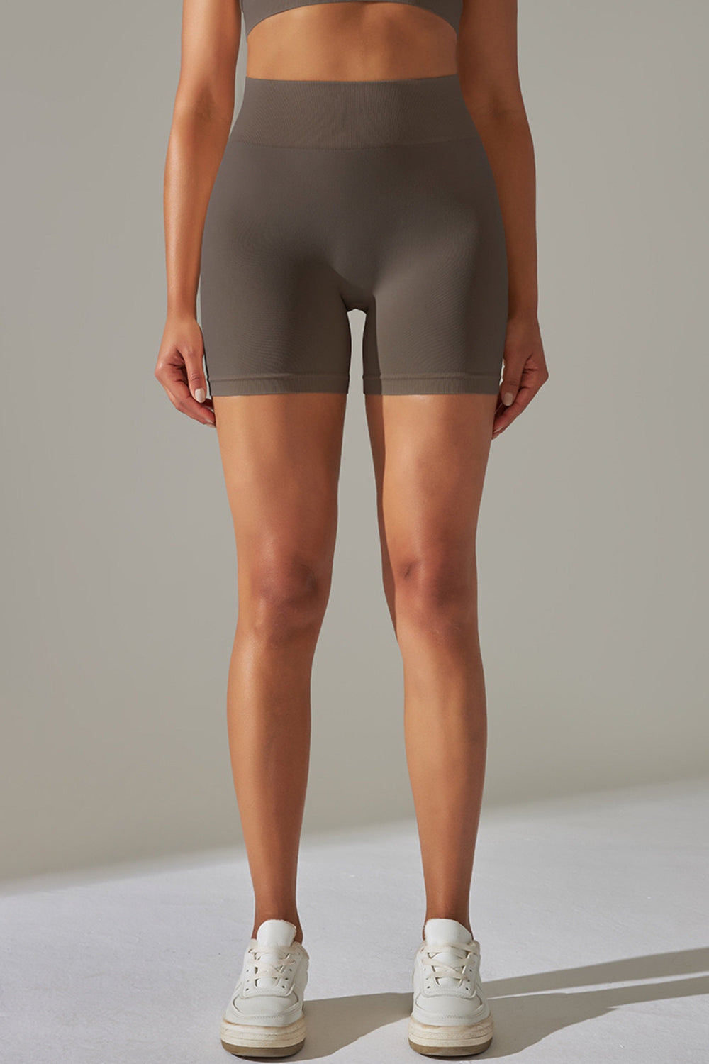 Kvinde iført mørke scrunch shorts og top, stående frontalt i helfigur. Benene let spredt og hænderne ned langs siden.

